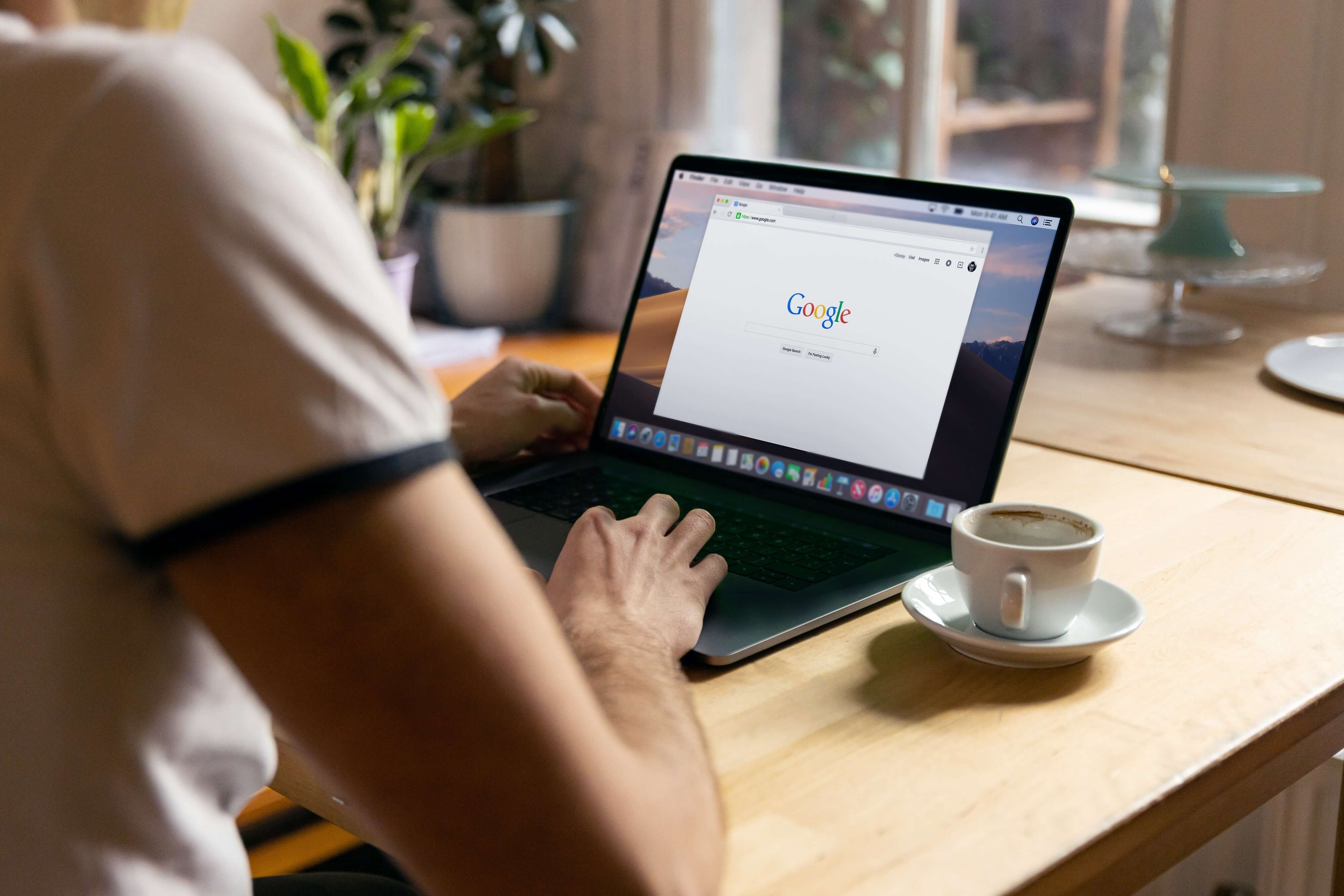 A young man sitting a MacBook who has Google open in his browser